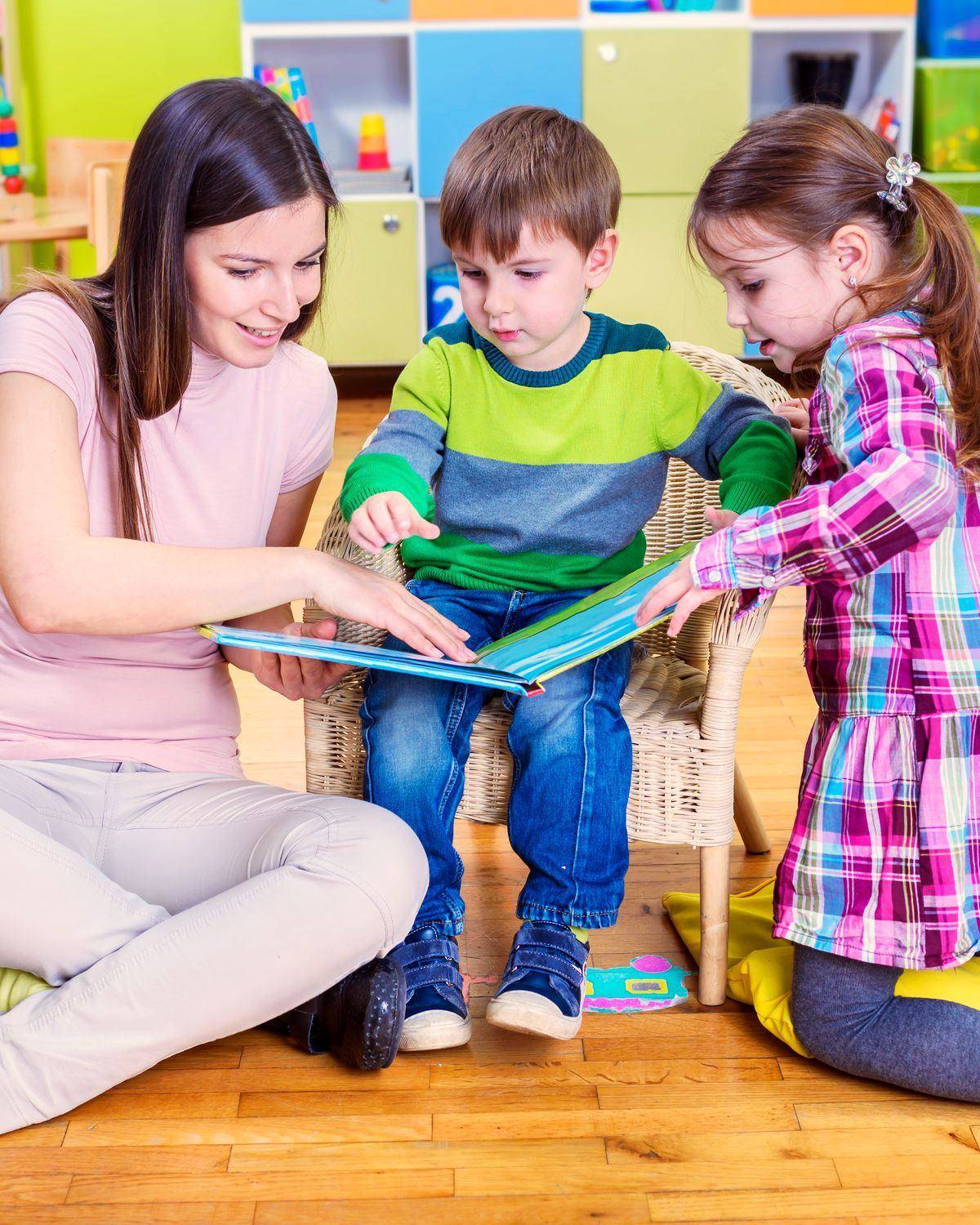 Een vrouw bekijkt met twee kleuters een prentenboek