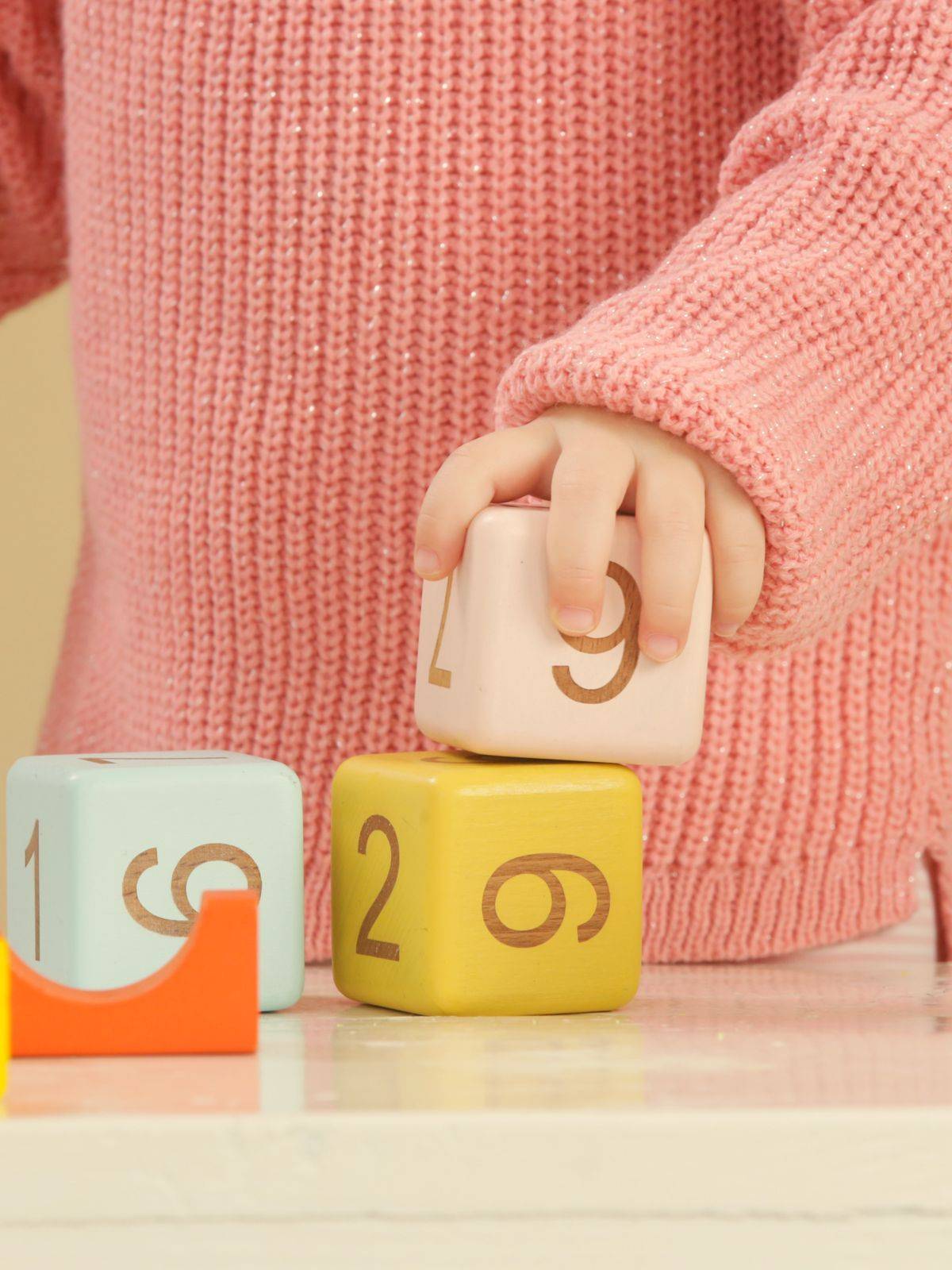 Kinderhand stapelt houten blokken met cijfers